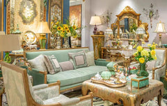 Decorative interior setting with furniture, mirrors, and floral arrangements.