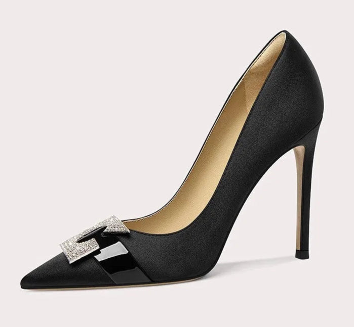 Black high-heeled shoe with a decorative bow on a light gray background
