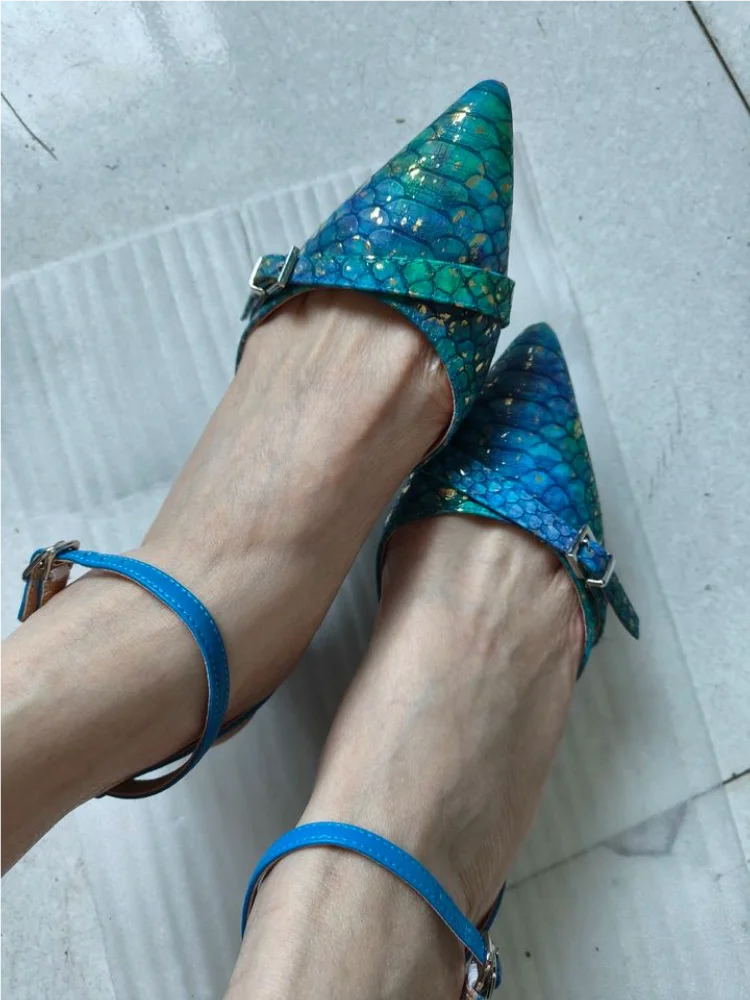 Blue and green glittery high-heeled shoes worn on a light gray floor.