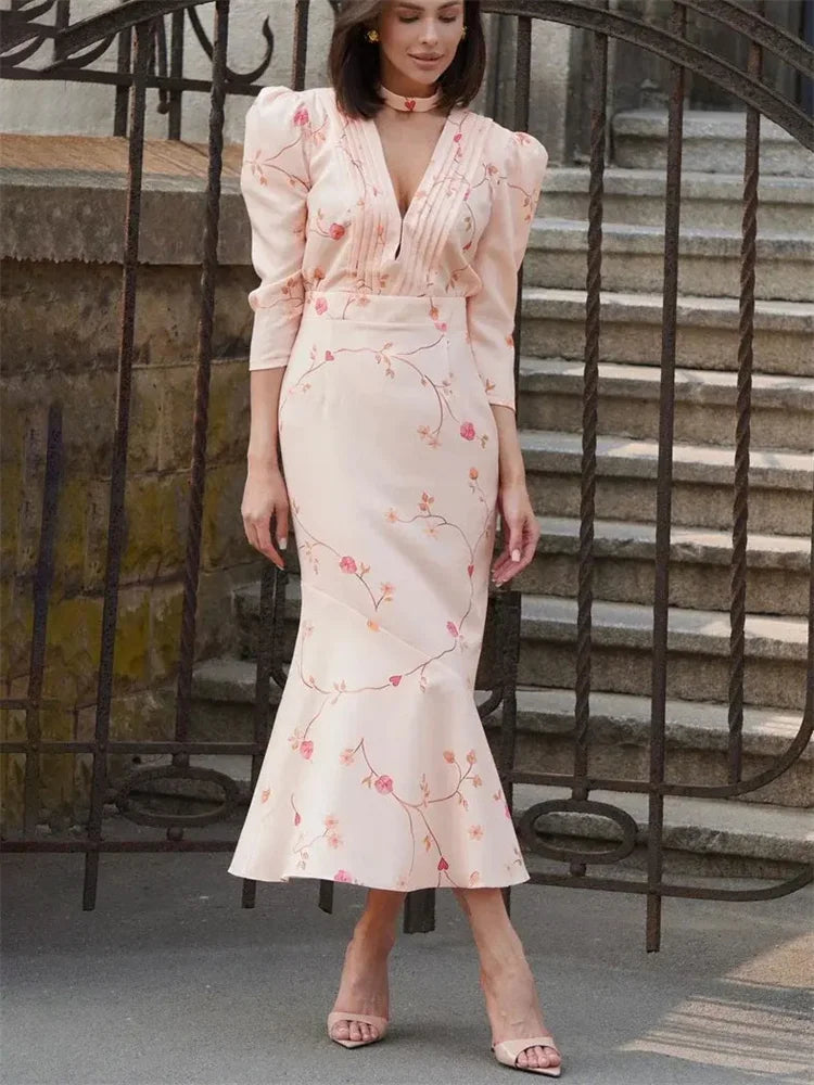 Woman wearing a floral dress standing in front of a metal gate.
