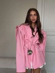 Woman wearing a pink coat with a patterned wall in the background