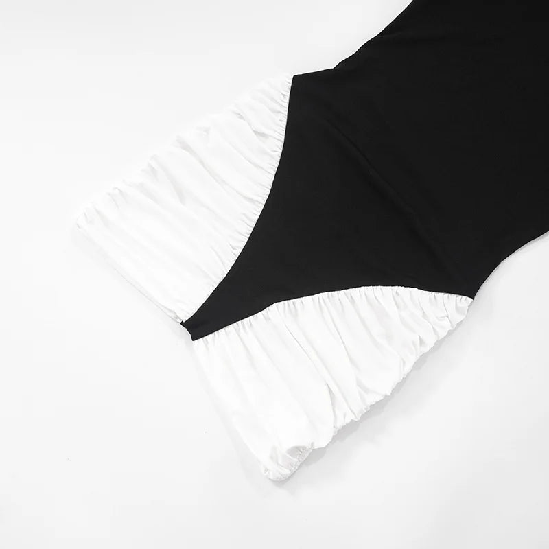Black swimsuit with ruffled white bottom on a light gray background