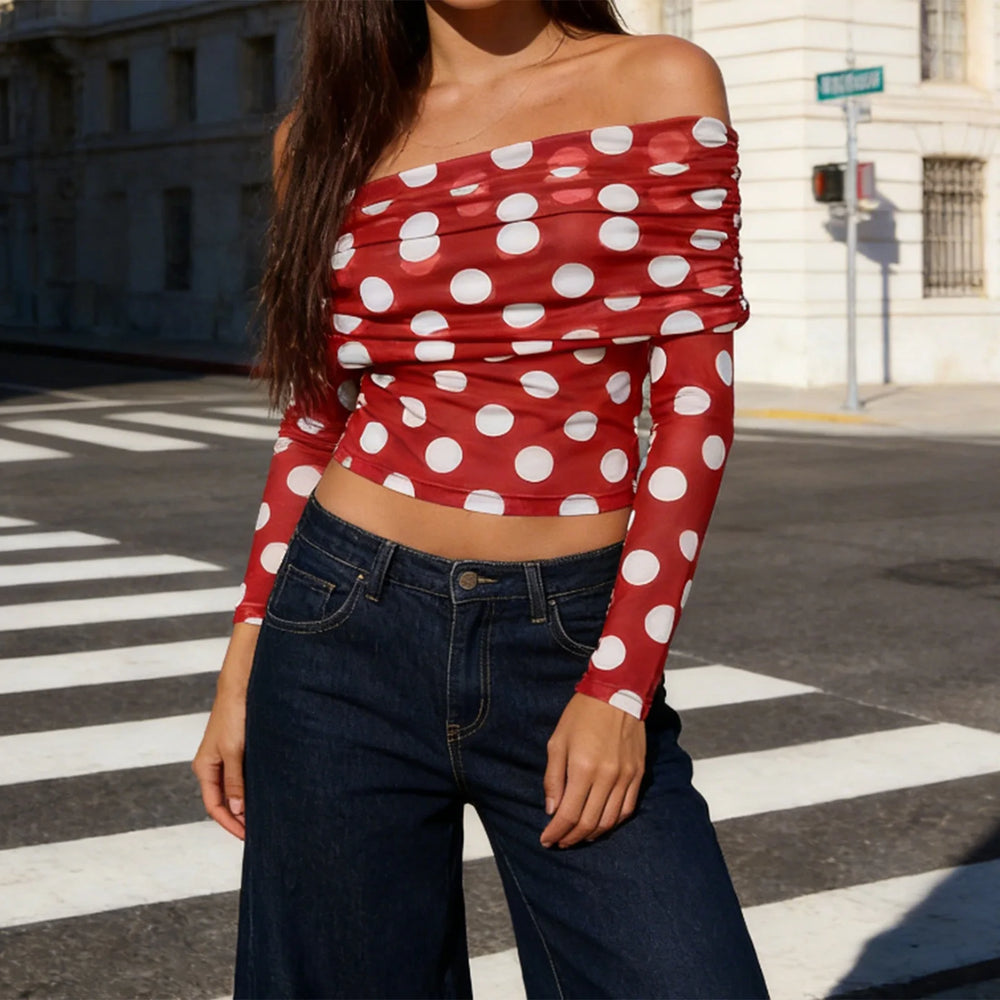 Person wearing a red polka dot top and blue jeans on a city street.
