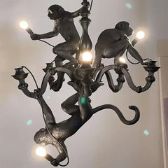 A playful retro monkey chandelier with three monkeys hanging from a branch, illuminating a modern coffee shop. Black