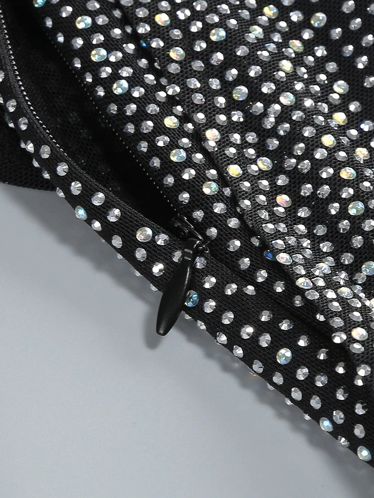 Black clutch bag with rhinestone embellishments on a light gray background