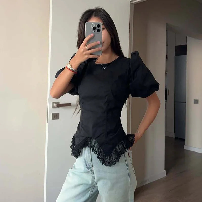 Person wearing a black top with lace details and light blue jeans, taking a mirror selfie.