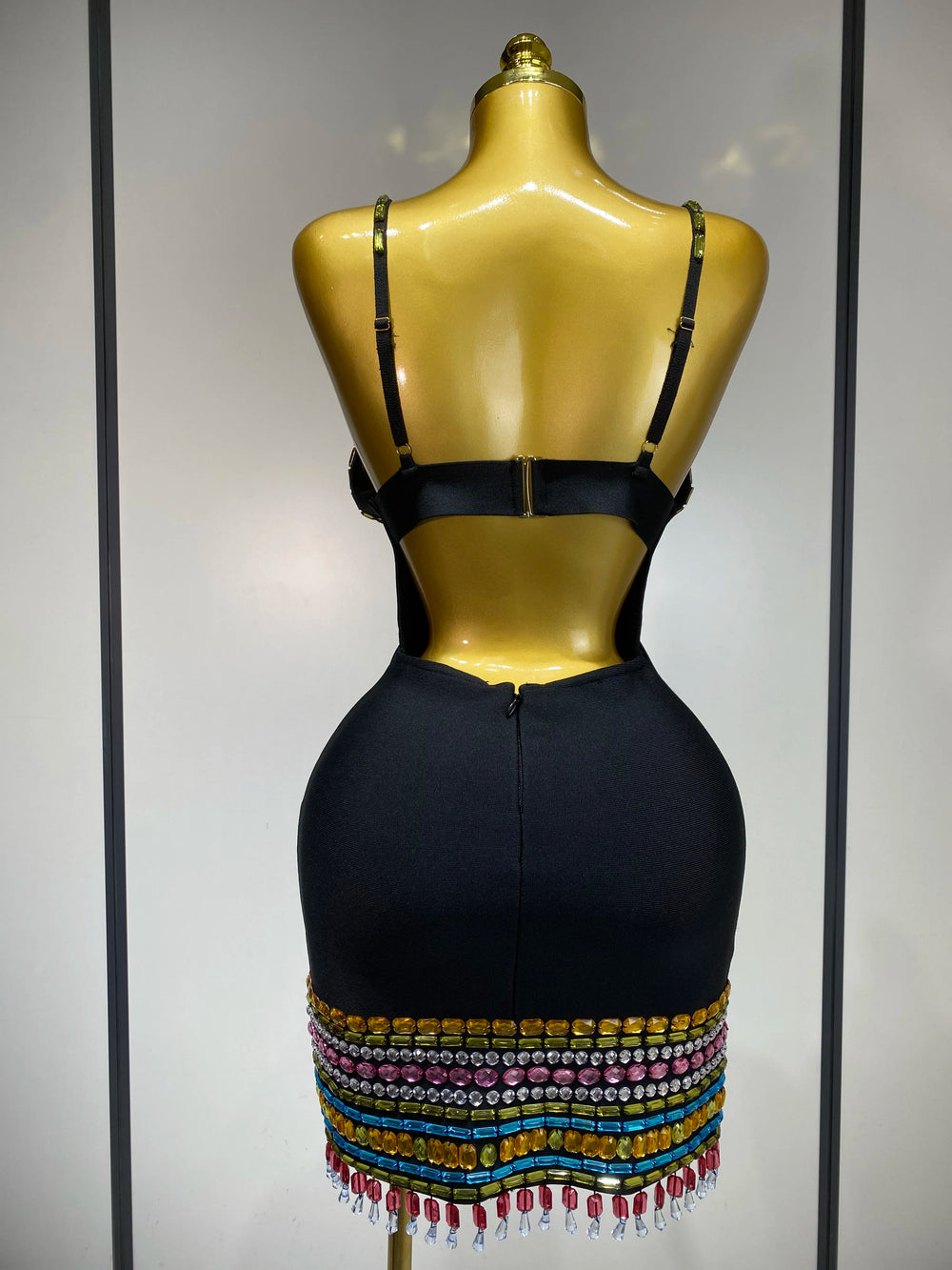 Black dress with colorful beading on a mannequin against a neutral background