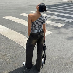 Person wearing a striped top and dark jeans standing on a crosswalk