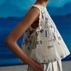 Woman wearing a white dress with blue patterns against a blue background