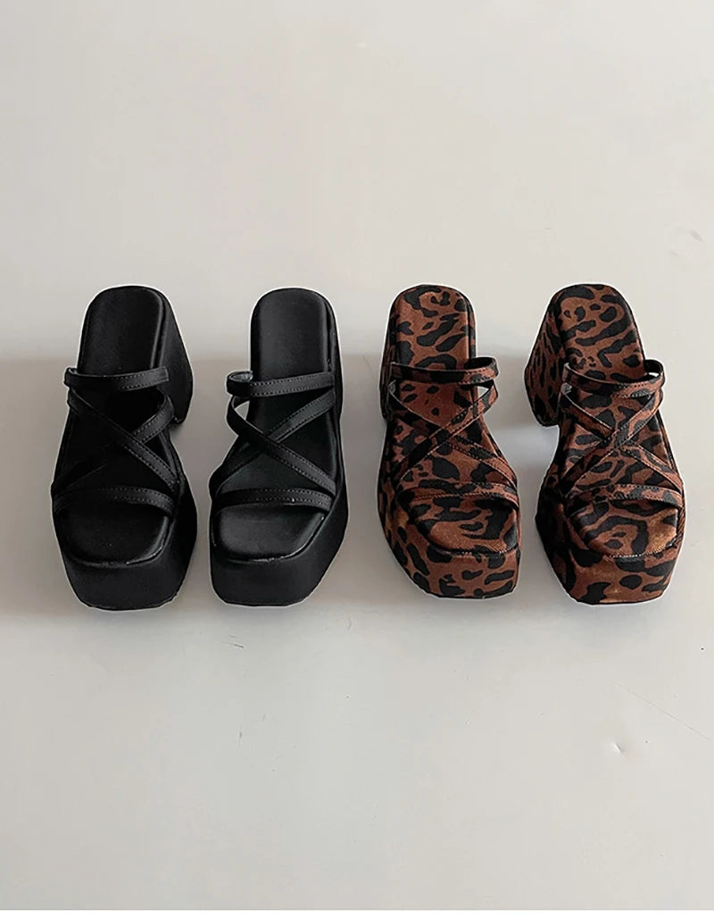 Two pairs of platform sandals, one black and one with leopard print, on a white background.