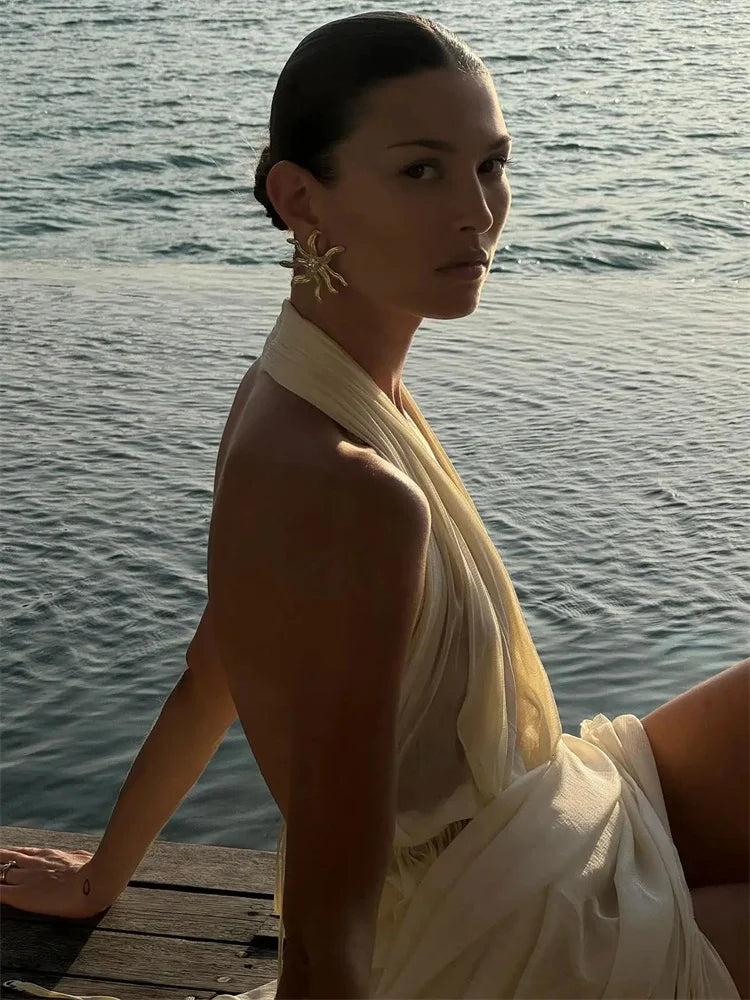 Woman in a white dress with a yellow scarf by the water