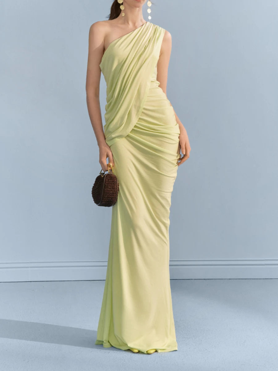 Model wearing one-shoulder draped maxi dress with a small bag