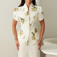 Woman wearing a white blouse with floral patterns on a plain background