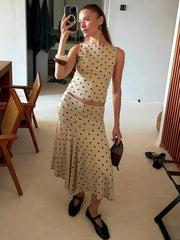 Woman in a polka dot dress taking a mirror selfie in a room.