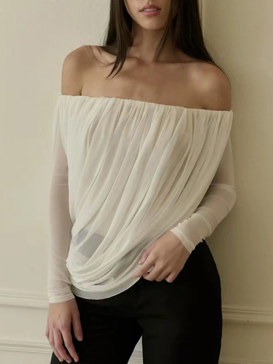 Woman wearing a white off-shoulder top against a plain background