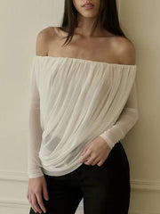 Woman wearing a white off-shoulder top against a plain background