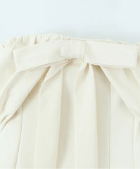 White blouse with a large bow detail on a light gray background