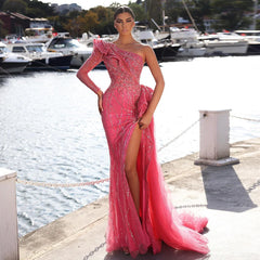 Woman in a pink evening gown standing by a waterfront with boats in the background