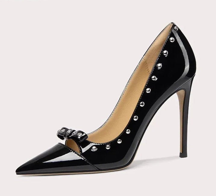 Black high-heeled shoe with studded details on a light gray background