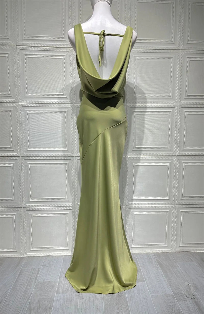 Green evening gown on a mannequin against a white paneled wall.