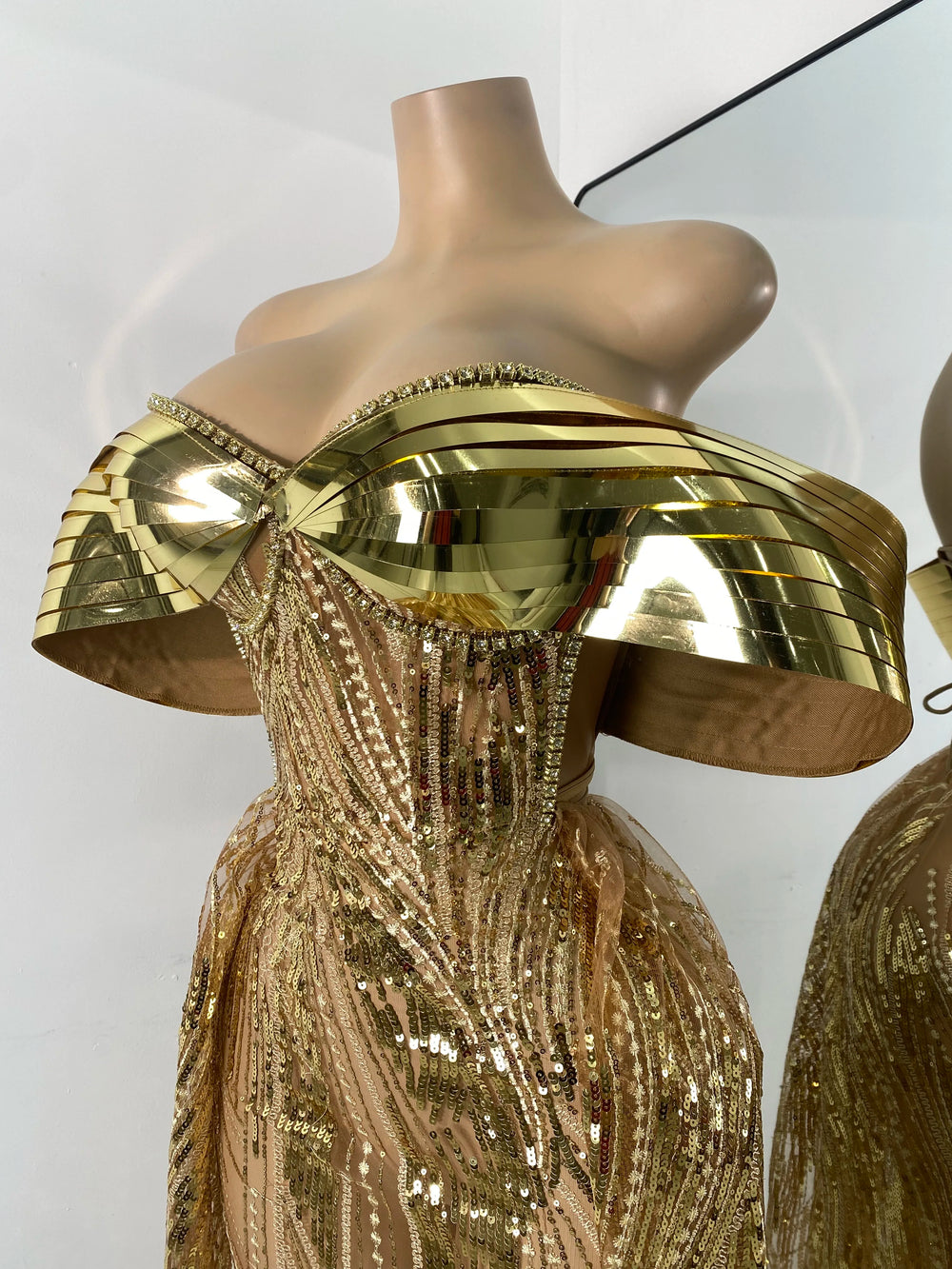 Gold dress with a unique design on a mannequin against a white background