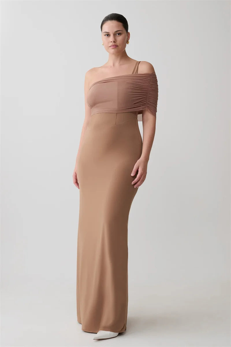 Woman wearing a long, one-shoulder brown dress on a white background