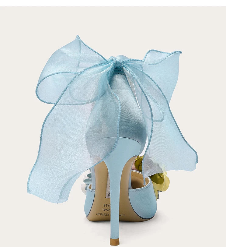 High-heeled shoe with a light blue sheer bow on a white background