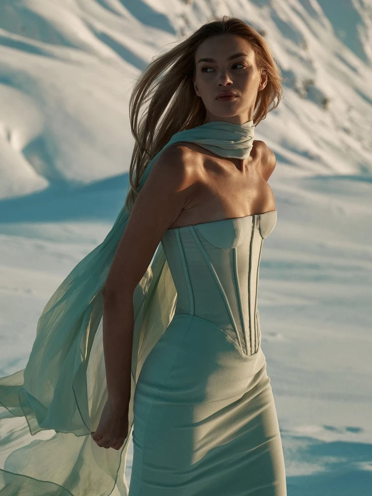 Woman in a light blue dress with a scarf in a desert setting