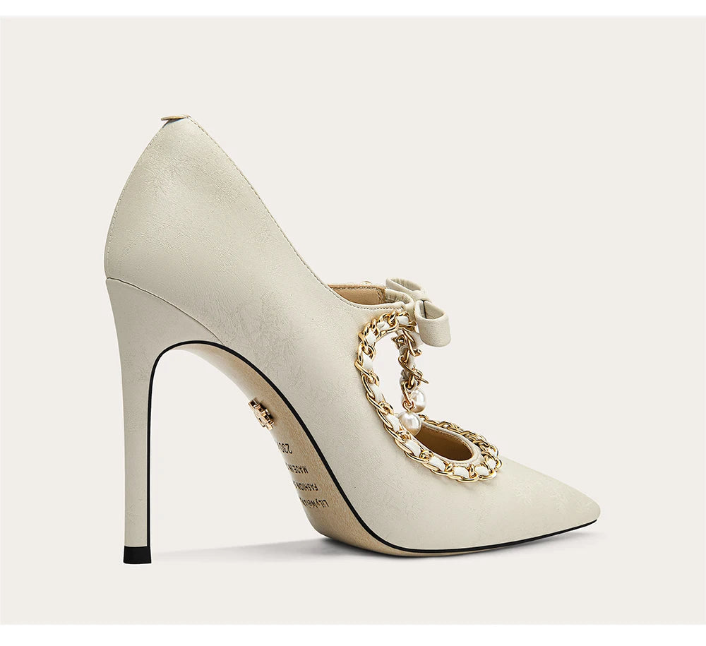 White high-heeled shoe with gold chain detail on a light gray background