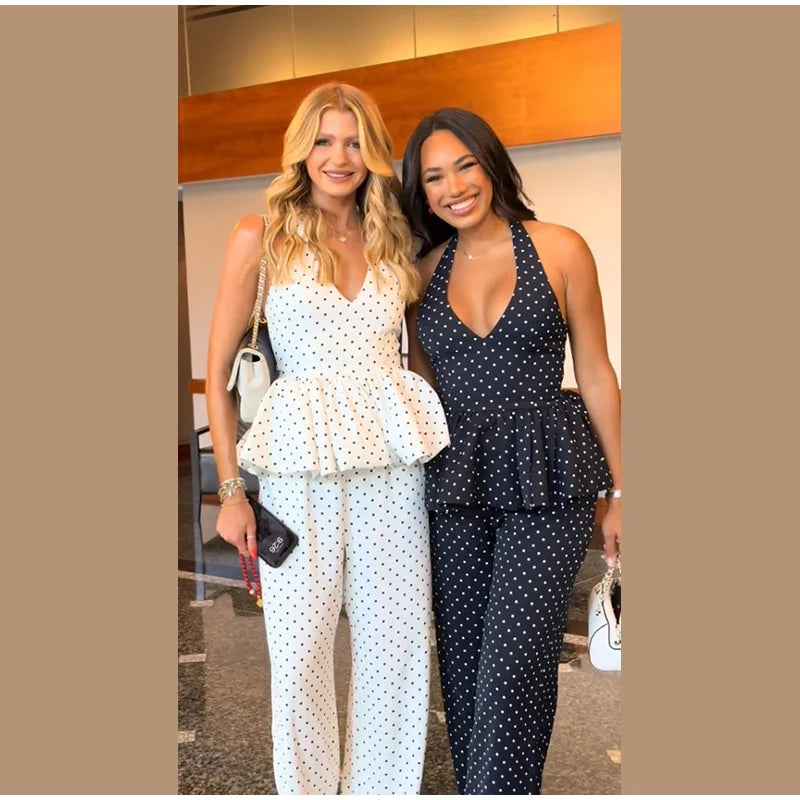 Two women wearing matching polka dot outfits standing together indoors.