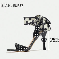 Black polka dot high-heeled shoe with a bow, size EUR37, on a white background.
