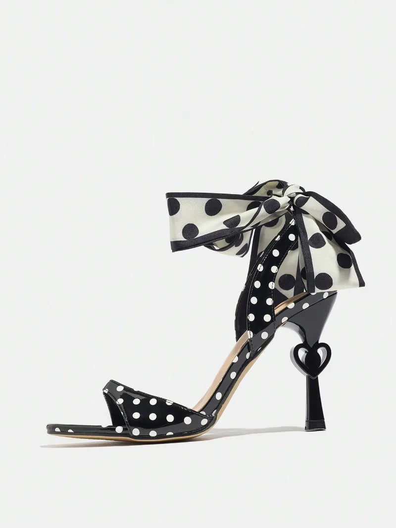 Black polka dot high-heeled shoes with a ribbon on a white background