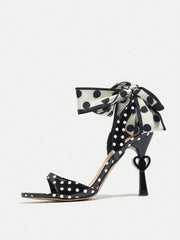 Black polka dot high-heeled shoes with a ribbon on a white background