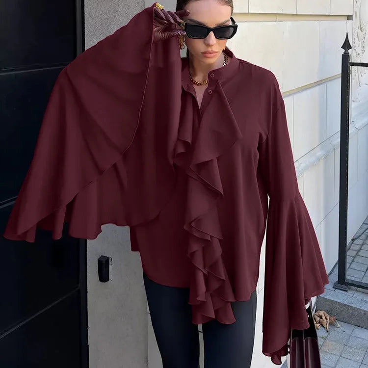 Woman wearing a burgundy ruffled blouse outdoors.