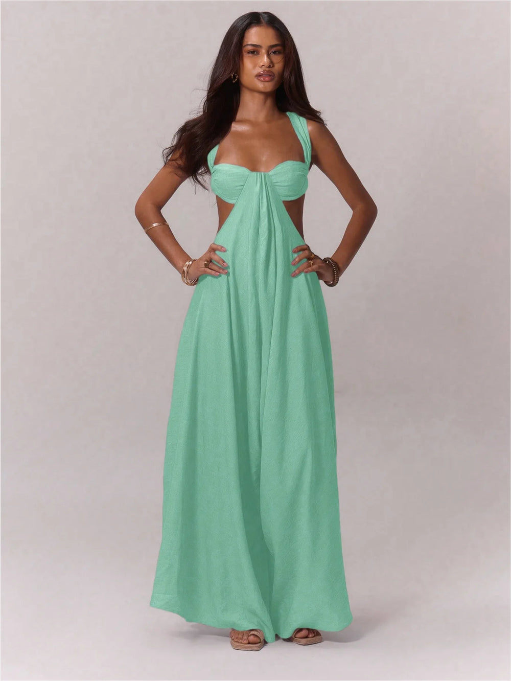 Woman wearing a green jumpsuit with a cut-out design on a plain background