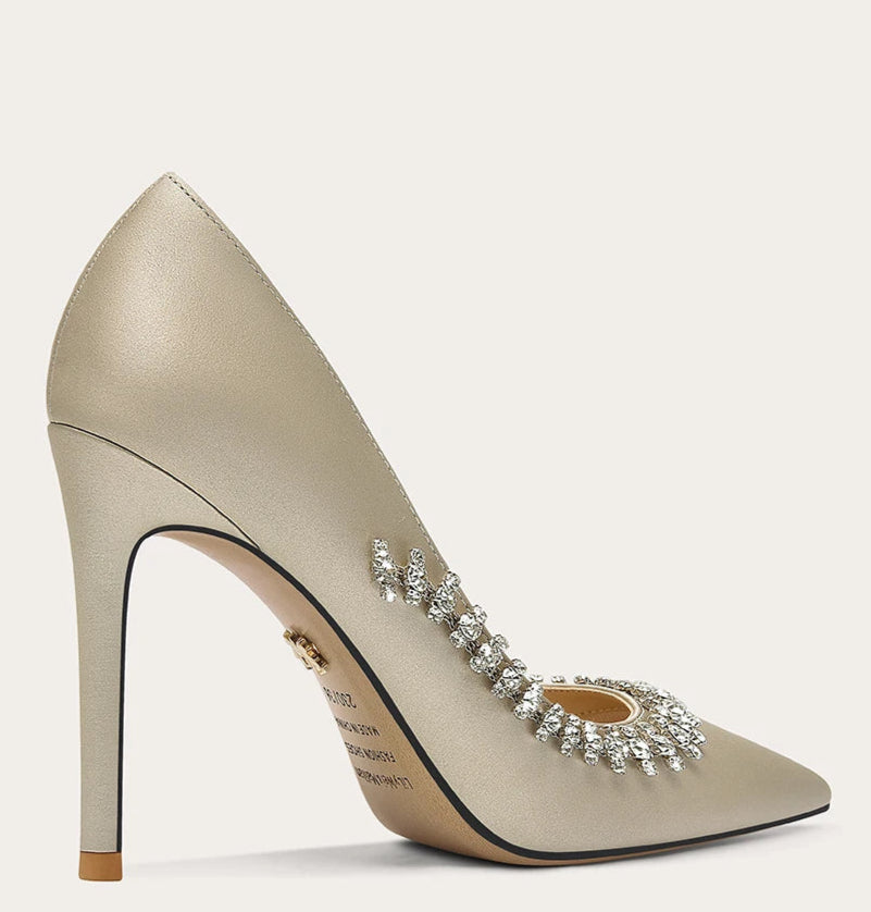Beige high-heeled shoe with embellishments on a light gray background