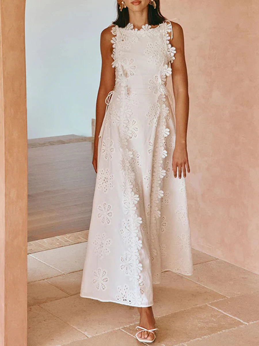 Woman wearing a white lace dress standing against a light pink wall.