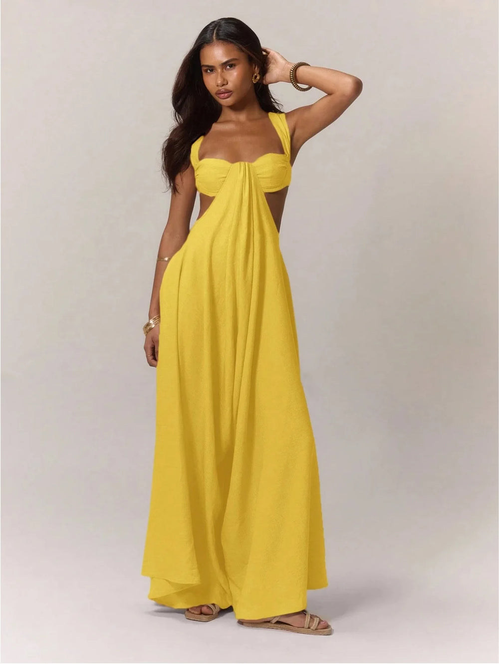 A woman wearing a yellow strapless jumpsuit against a plain background