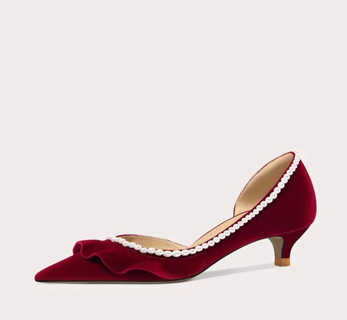 Red high-heeled shoe with pearl details on a light gray background