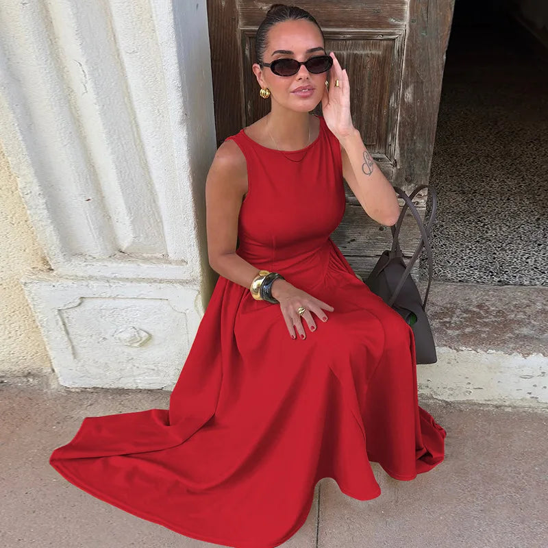 Woman in a red dress sitting against a stone wall.