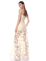 Woman wearing a strapless dress with a sheer, circular patterned overlay on a white background