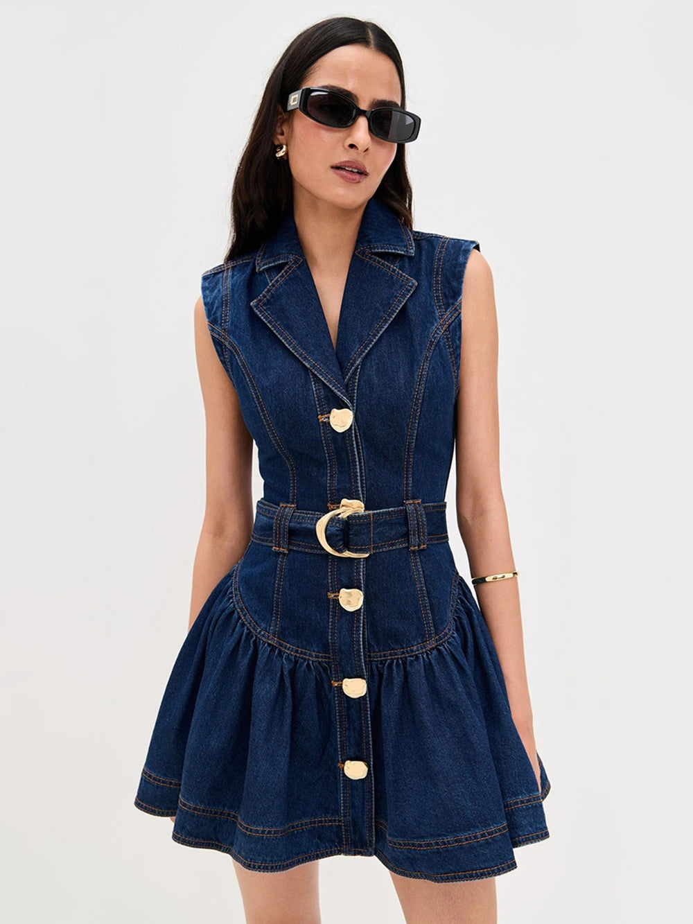 Woman wearing a denim dress with gold buttons
