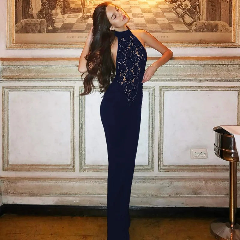 Woman in a navy blue lace dress standing in an elegant room with decorative wall art.