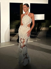 Woman in a white lace dress standing indoors with a modern architectural background
