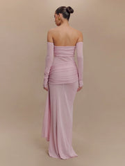 Woman wearing a pink off-shoulder gown with long sleeves on a beige background