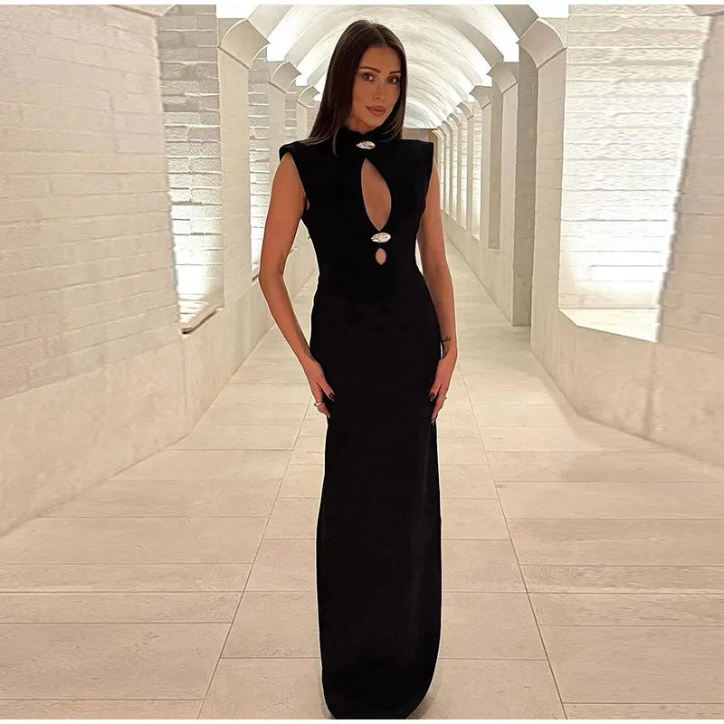 Woman in a black evening gown standing in a modern architectural hallway.