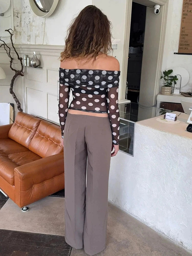 Person wearing a polka dot top and gray pants in a living room setting.