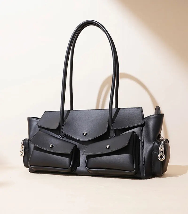 Black handbag with multiple compartments on a beige background