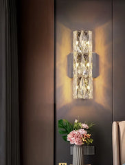 An elegant crystal wall light with a long arm and a decorative shade, adding a touch of luxury to a bedroom.