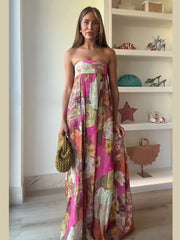 Woman in a colorful strapless dress standing in a room with shelves displaying various items.